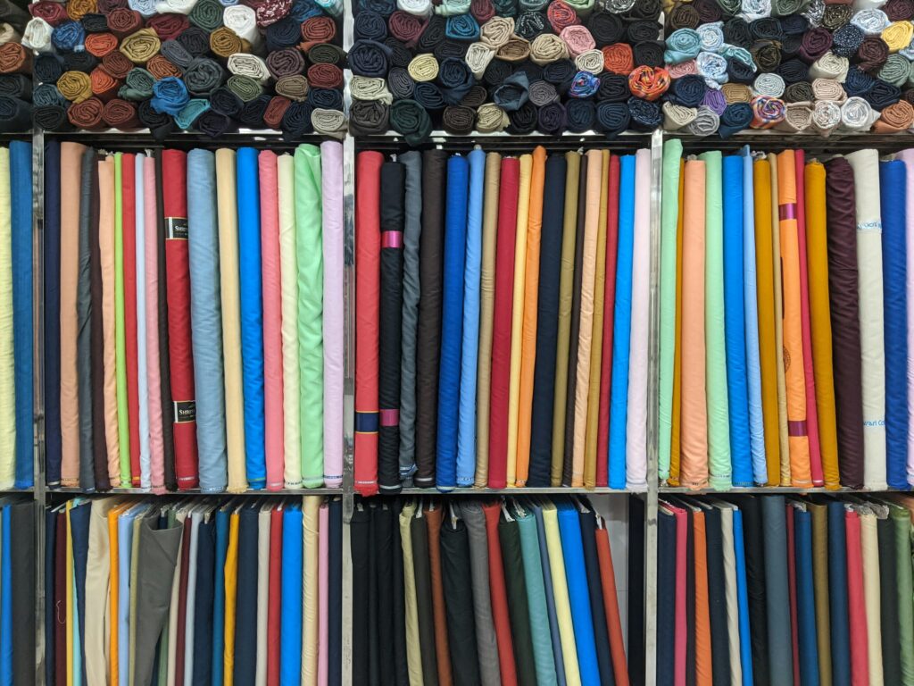 Colorful fabric rolls neatly arranged on shelves, showcasing a variety of textures and materials.