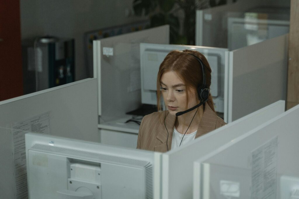 Focused woman in a call center wearing headphones, working at a desk.