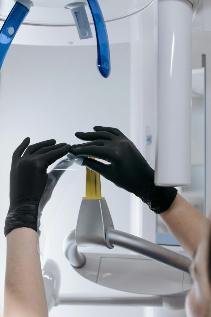 Focused view of hands in black gloves setting up dental equipment in a clinic environment.