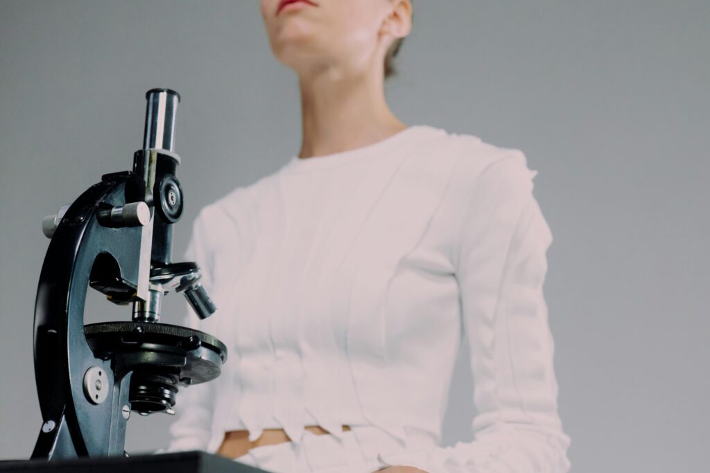 Woman scientist examining samples with microscope in studio setting.